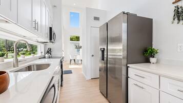 Una cocina moderna con electrodomésticos de acero inoxidable, armarios blancos y vistas al comedor.