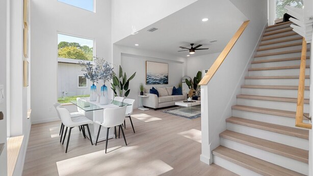 A spacious living area with a dining table, white sofas, and a staircase. - Luxury Modern Comfort in Historic St Augustine (St. Augustine)