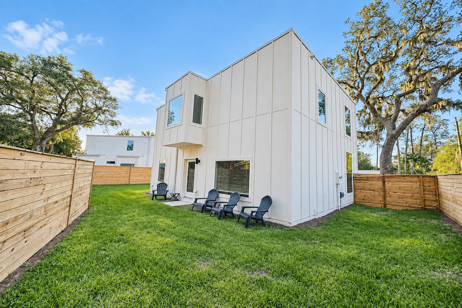 A modern two-story house with a flat roof and a covered patio area.