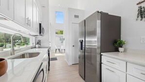A modern kitchen with stainless steel appliances, white cabinetry, and a view to the outdoors. - Luxury Modern Comfort in Historic St Augustine (St. Augustine)