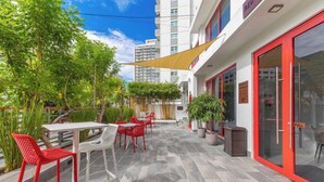 An outdoor patio area with red and white chairs, a table, and potted plants. - Red Door Inn (San Juan)