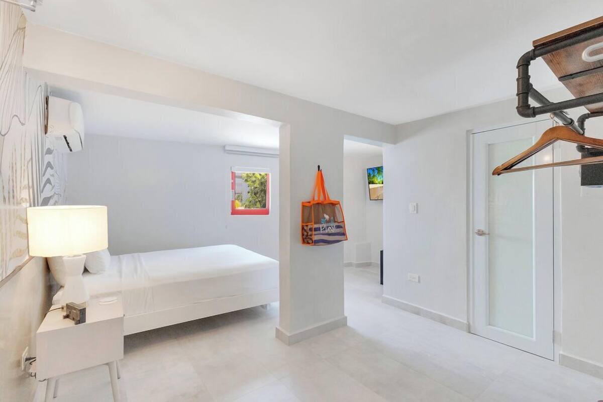 A modern bedroom with a bed, bedside table, and a hanging garment bag.