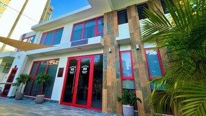A modern hotel with a two-story facade, red-framed windows, and a central entrance with a glass door. - Red Door Inn (San Juan)