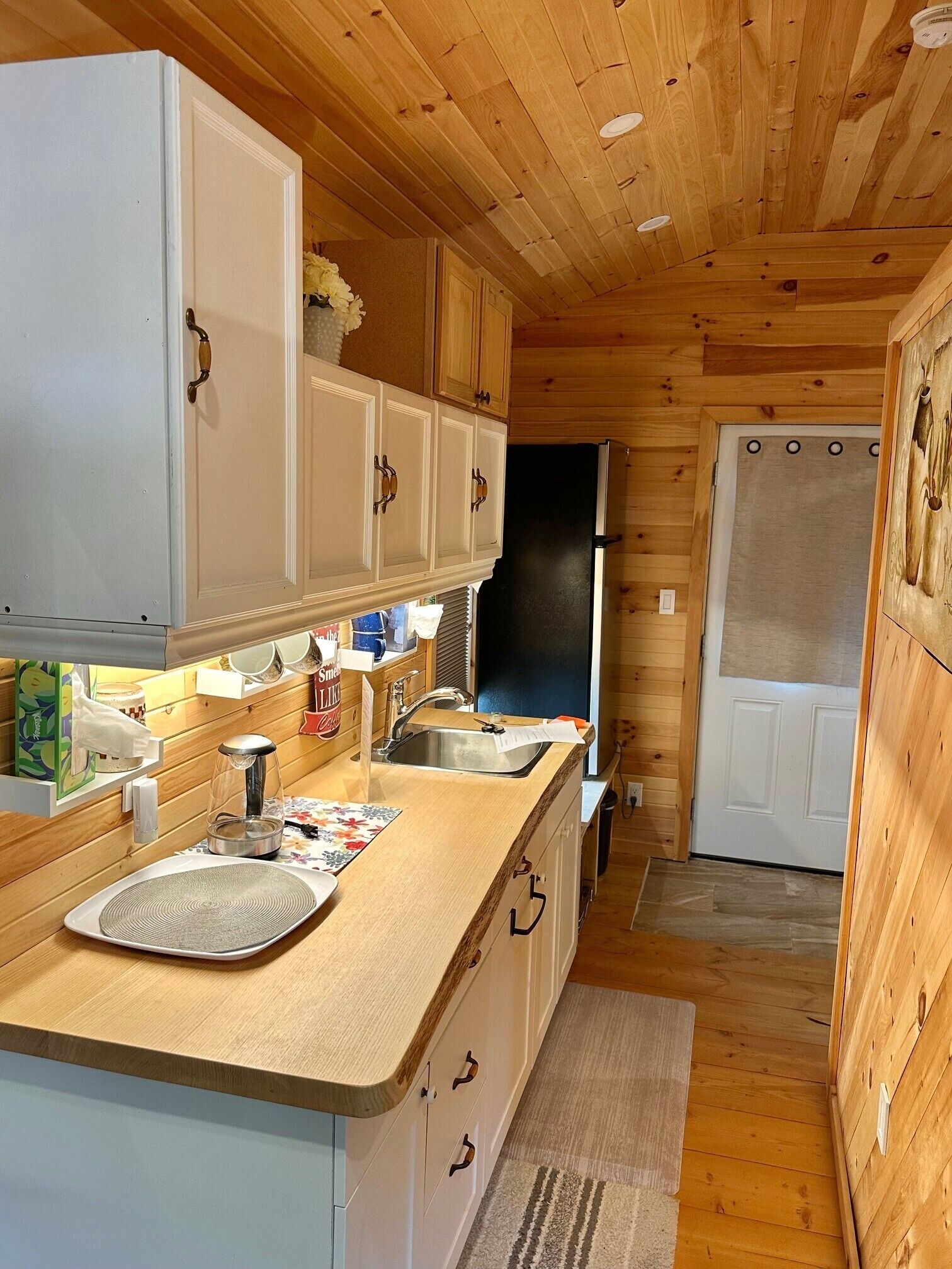Eine kleine Küche mit Holzschränken, einem Spülbecken und einem Kühlschrank.