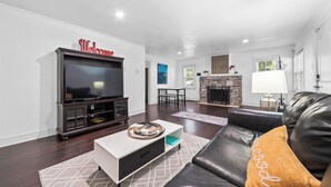 A modern living room with a flat-screen TV, a fireplace, a leather sofa, and a coffee table.