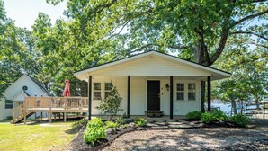 A single-story house with a porch, a small deck, and a front yard with a gravel path.