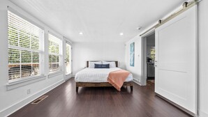 A bedroom with a large bed, white walls, and a sliding door.