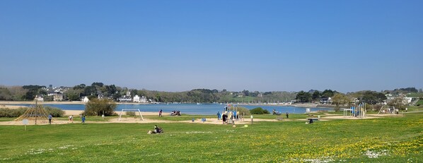 A park with a playground, a sandy area, and a lake. - At the foot of Plage de la falaise (Guidel)
