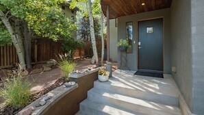Ein modernes Haus mit einer Holzterrasse, einer Betonstufe und einer dunklen Tür.