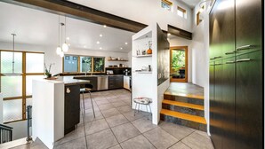 Eine moderne Küche mit einer zentralen Kochinsel, Edelstahlgeräten und einer Treppe, die in eine obere Ebene führt.