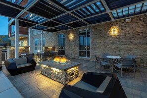 An outdoor patio with stone walls, a fire feature, and seating. - Springhill Suites By Marriott Columbus West (Columbus)