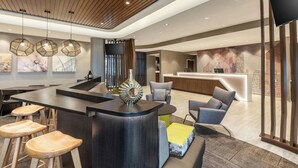 En modern hotellobby med en central bar, en sittgrupp och en receptionsdisk.