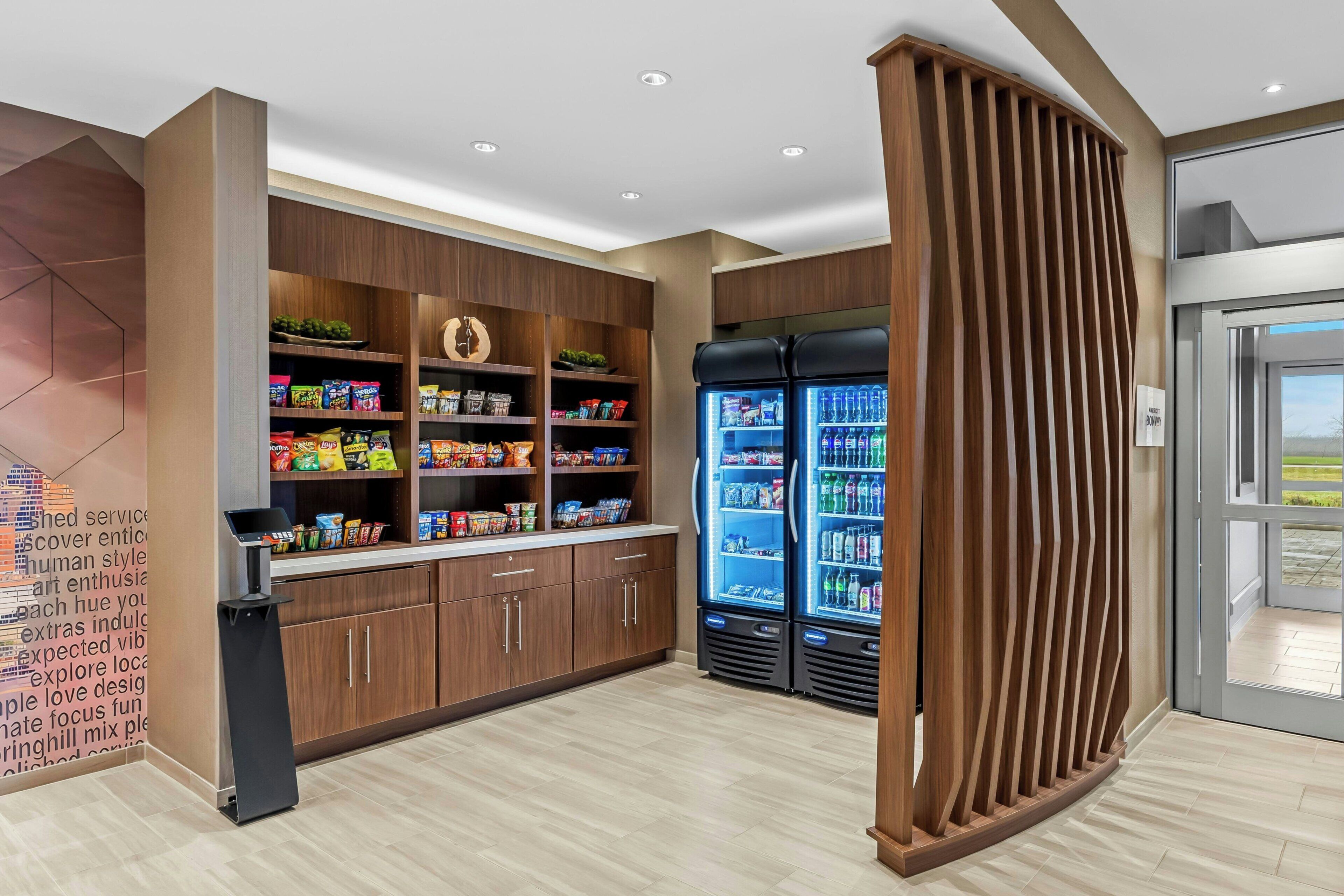 A modern kitchen with wooden cabinets, a refrigerator, and a variety of snacks.
