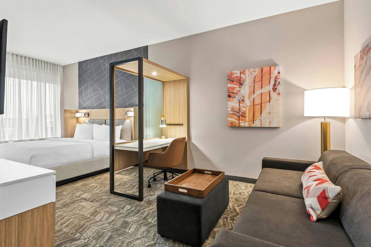 A hotel room with a bed, a desk, a sofa, and a small table.