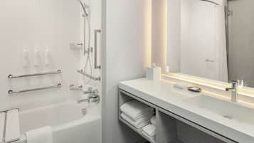 A modern bathroom with a bathtub, a large mirror, a vanity with a sink, and towel storage.