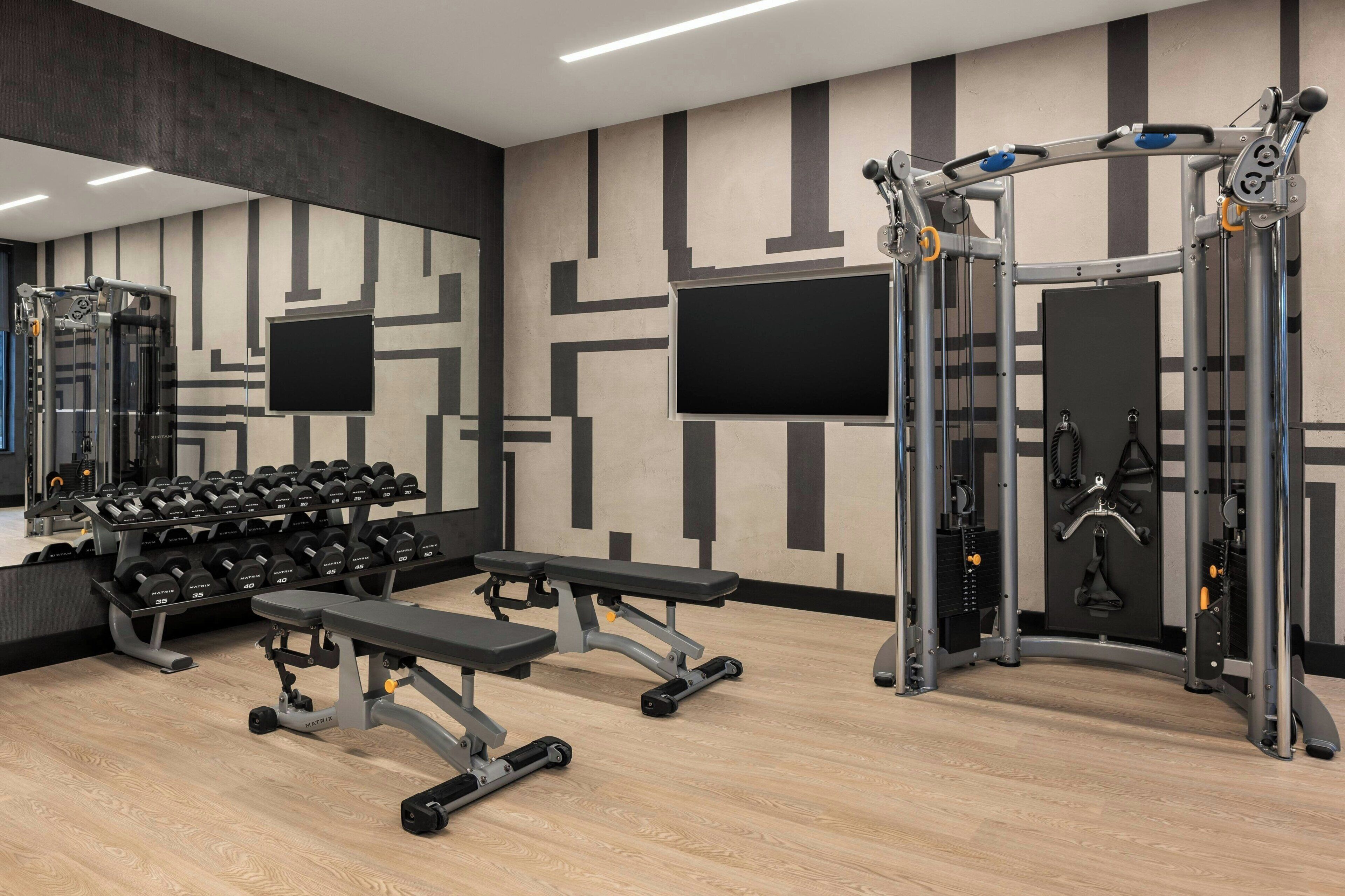 A gym with weightlifting equipment, benches, and dumbbells.