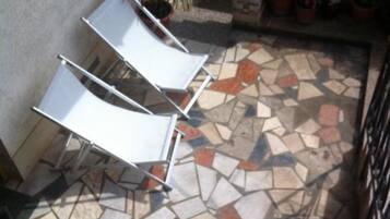 A tiled patio with a white metal table and chairs.