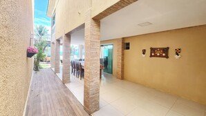 A corridor with a wooden floor, beige walls, and a glass door leading to a dining area. - Condomínio Esmeralda do Mar (Ipojuca)
