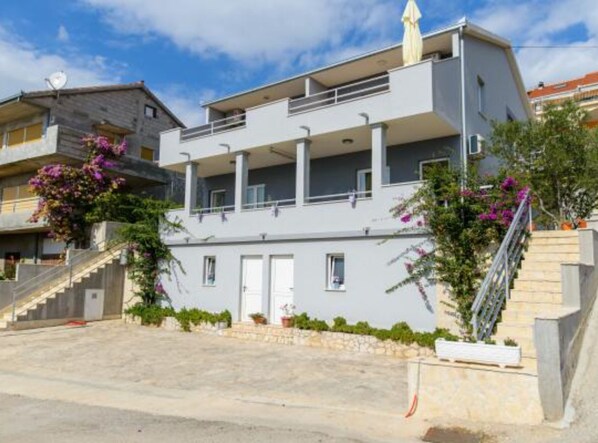 A modern two-story building with balconies, a staircase, and potted plants. - Apartments Nela (Okrug)
