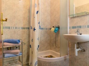 A bathroom with a shower, a sink, and a towel rack. - Apartments Nela (Okrug)