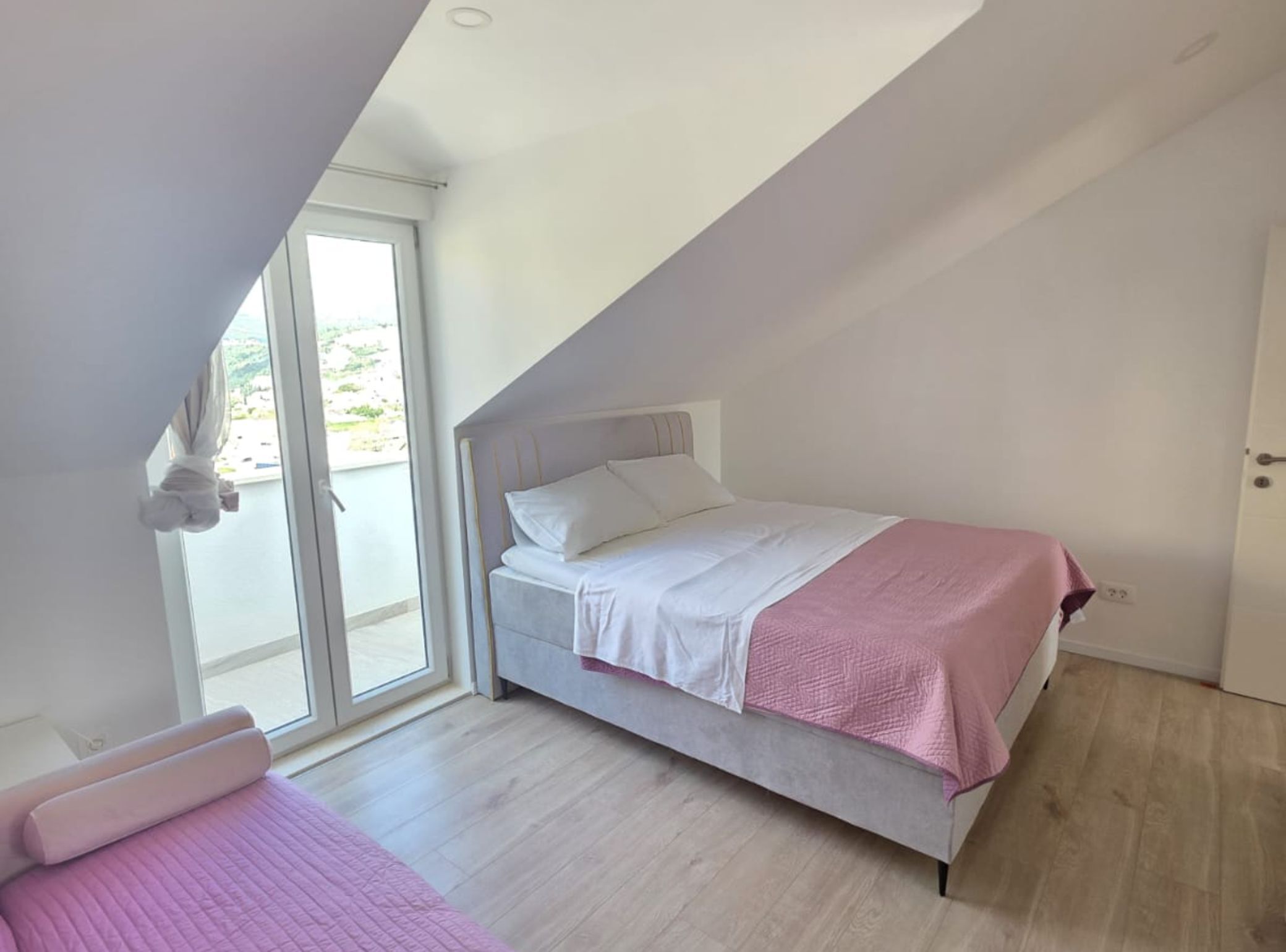 A bedroom with a bed, a window, and a door.