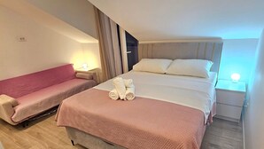 Una habitación de hotel con una cama, un sofá y una mesita de noche con lámpara.