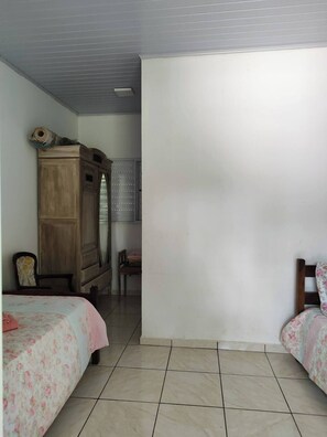 Ein Schlafzimmer mit zwei Betten, einem Holzschrank, einem Stuhl und einem kleinen Tisch.