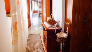 A hallway with a wooden cabinet, a wicker basket, and a patterned rug. - Casa Anni `70 - Sardegna (Burgos)