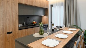 Una cocina moderna con armarios de madera, encimera negra y comedor con una mesa de madera para cuatro.