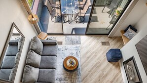 A modern living room with a gray sectional sofa, a wooden coffee table, and a glass dining table with chairs.