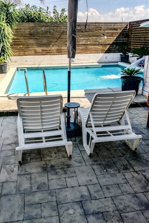 A pool area with two white lounge chairs and a small table, surrounded by a wooden fence and potted plants. - Villa Lucia - Apulia (Lucera)