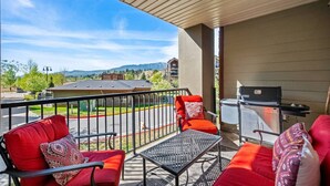 A balcony with outdoor seating, a grill, and a view of a residential area with houses and mountains. - The Dragonfly | Pool/Hot Tub | Lake Access | Kayak (Invermere)