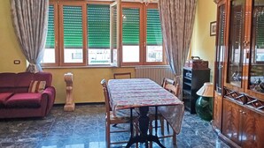 Ein Zimmer mit Esstisch, einer Couch, einem Chandelier und einem Schrank.