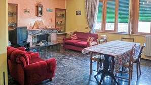Ein Wohnzimmer mit Kamin, roten Sofas, einem Esstisch und einer Kristallleuchter.