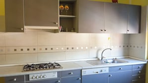 Eine Küche mit grauen Schränken, einem Gasherd, einem Geschirrspüler und einer Spüle.
