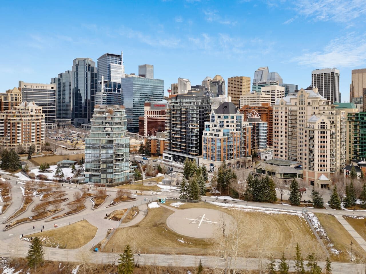 A cityscape with modern high-rise buildings, a central open plaza, and surrounding greenery.