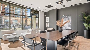 A modern conference room with a large table, comfortable seating, and large windows offering a city view.
