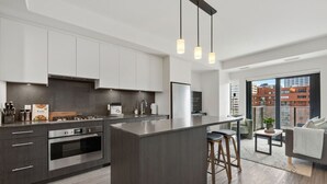 A modern kitchen with a central island, stainless steel appliances, and pendant lighting.