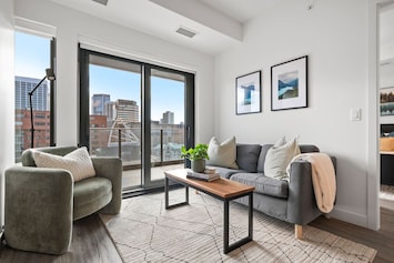 Living room with a Smart TV, board games, cozy seating option & floor-to-ceiling, south-facing windows with access to the wraparound balcony.