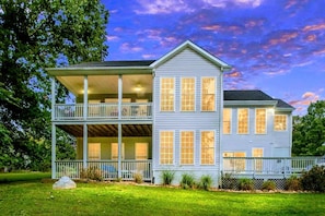 A two-story house with a balcony, a covered porch, and a well-maintained lawn.