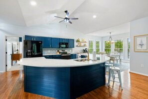 A modern kitchen with a central island, dark blue cabinets, and a ceiling fan. - Lakefront Lake Anna, Boat Dock, Hot Tub, Deck View (Mineral)