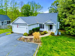 A two-story residential building with a garage, a front porch, and a well-maintained lawn.
