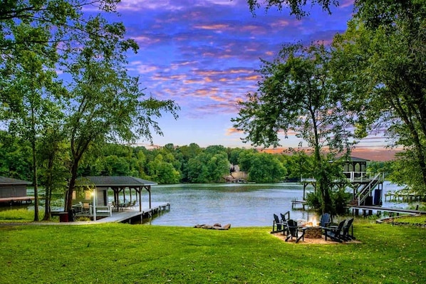 A lakeside view with a gazebo, dock, and outdoor seating area.