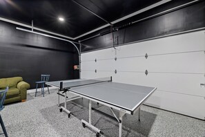 A ping pong table in a room with a black wall and a white door.