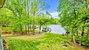 A lakeside view with a dock, grassy area, and trees.