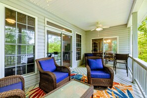 A covered porch with wicker furniture and a patterned rug.