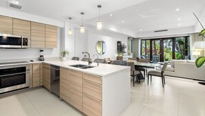 Una cocina moderna con electrodomésticos integrados, una zona de comedor y un espacio de estar con un ventanal grande.
