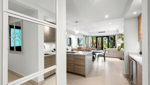 Una cocina moderna con una isla central, un área de comedor con sofá y vistas a zonas verdes.