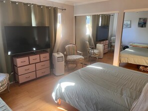 A hotel room with a large bed, a TV, a dresser, a chair, and a bedside table.