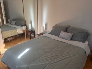 A bedroom with a large bed, two bedside tables, and a mirror.